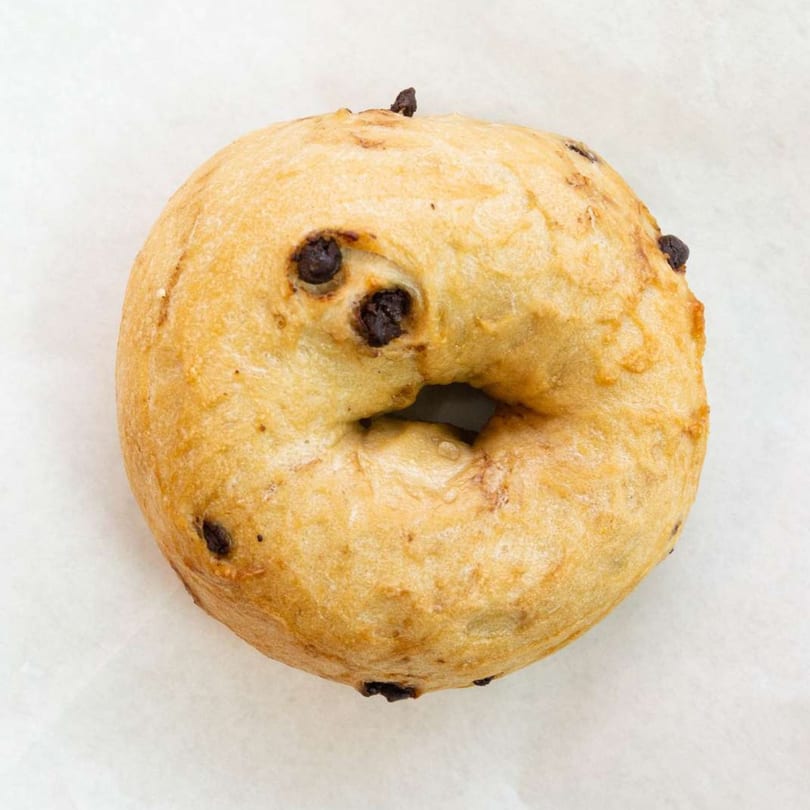 A golden-brown chocolate chip bagel from Raceway Bagels on a white surface.