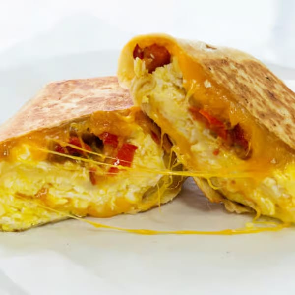 A Raceway Bagels breakfast quesadilla, cut in half, revealing melted cheese, scrambled eggs, and red peppers.
