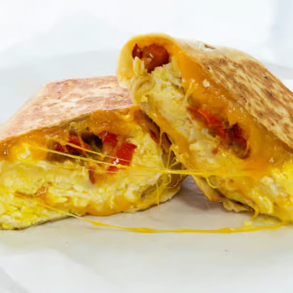 A Raceway Bagels breakfast quesadilla, cut in half, revealing melted cheese, scrambled eggs, and red peppers.